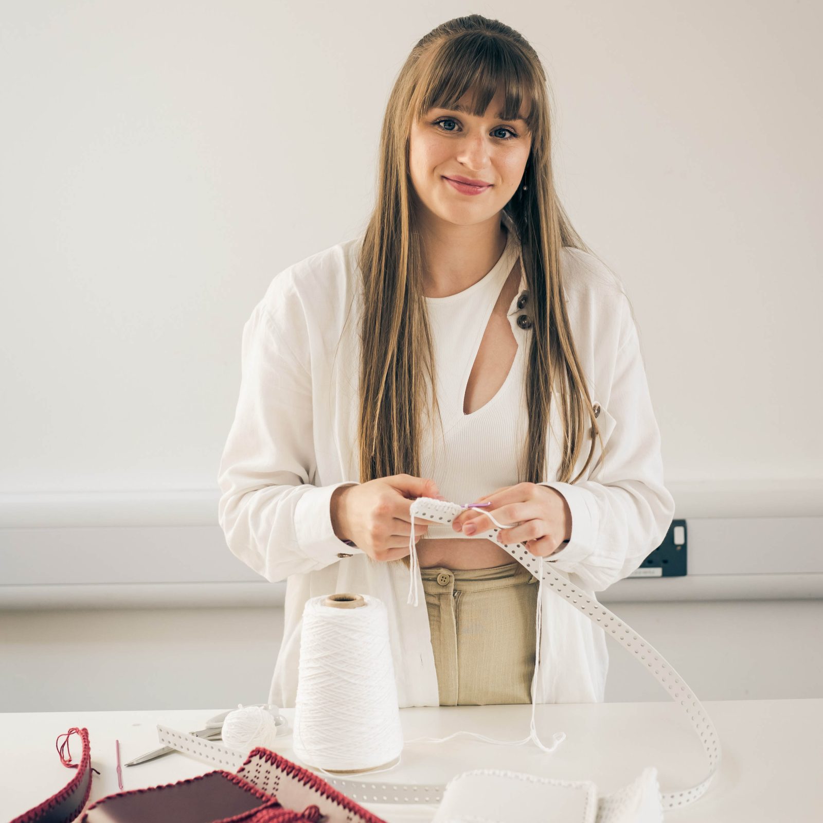 woman dressed in white holding a white leather strap