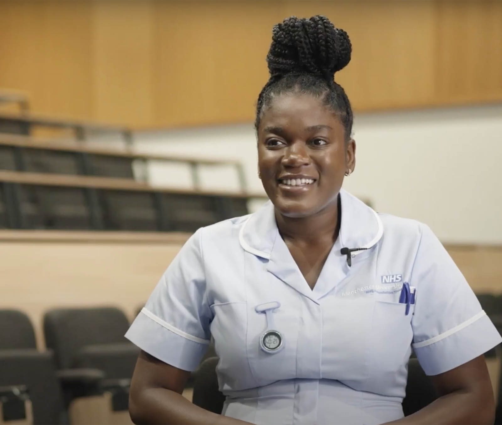 A woman in a nurse's uniform sitting in a lecture theatre
