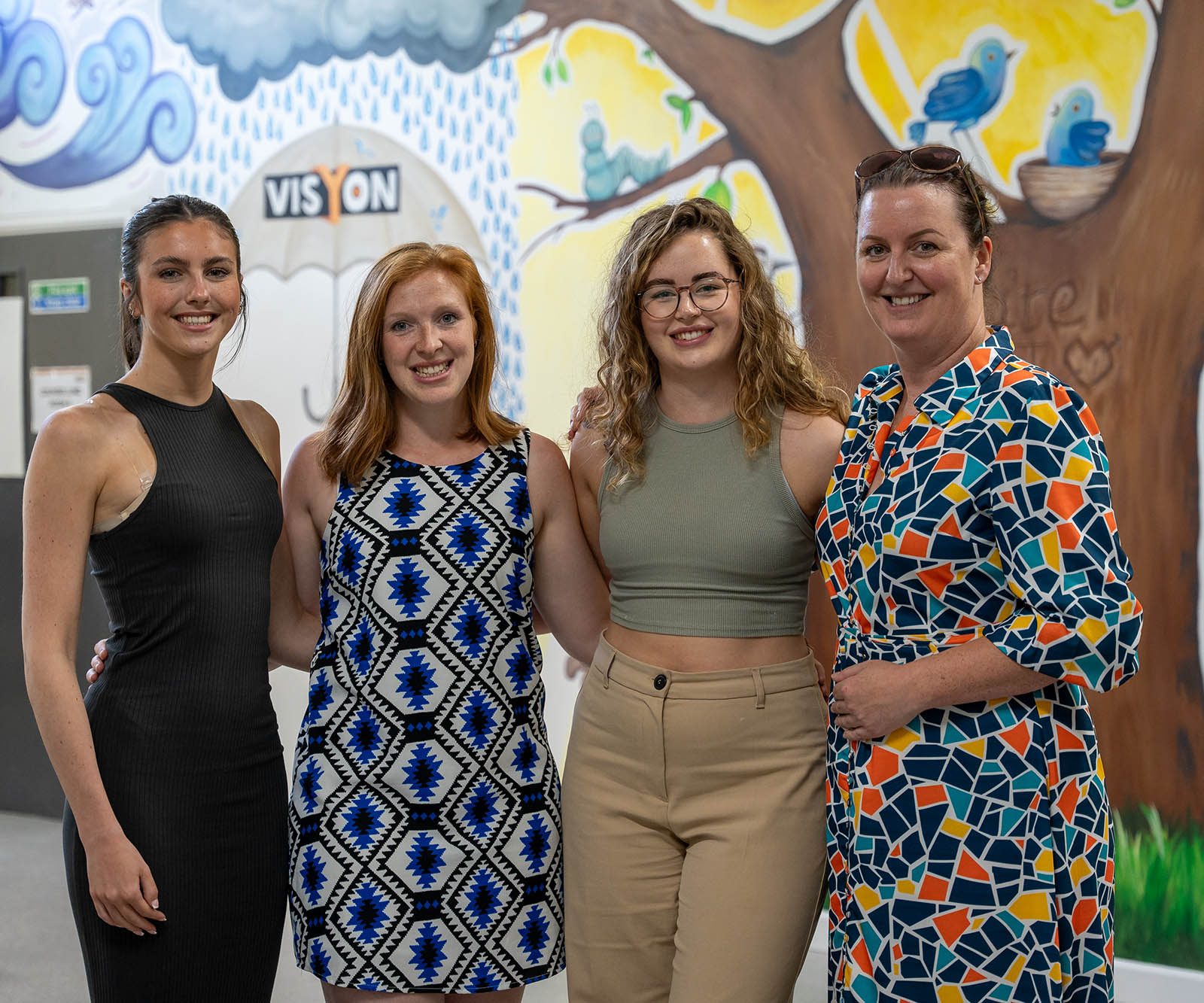 a group of four women looking to camera smiling