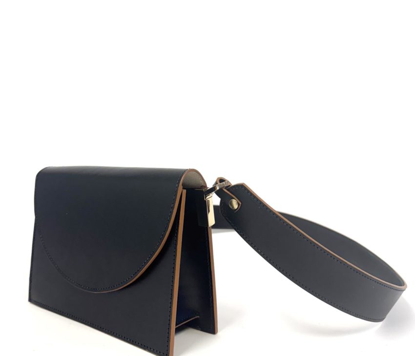 A small black leather handbag with brown edges, a flap fastening, and a wide wrist strap attached to one side. The bag is photographed against a plain white background.